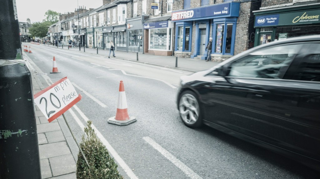 A car speeds past a handmade 20mph sign on Bishy Road