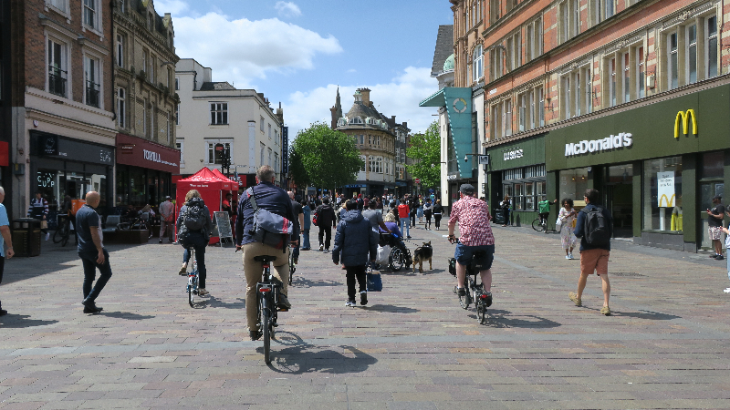 Cyclists and pedestrians both using a high street in Leicester city centre.